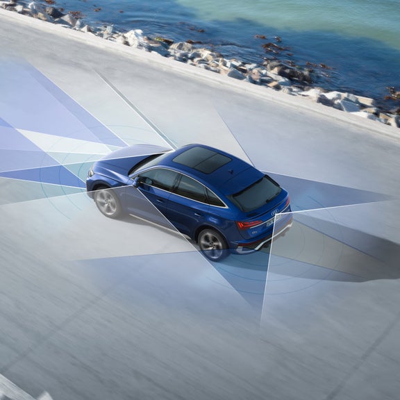 Blue car driving near the ocean with dynamic sensor graphic overlay.