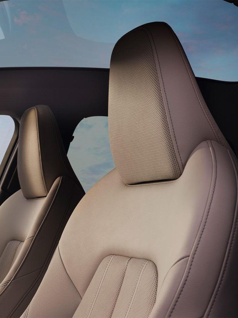 Vordersitze der Audi A5 Limousine unter einem großen Glasdach, Hintergrund mit Blick auf modernes Gebäude.
