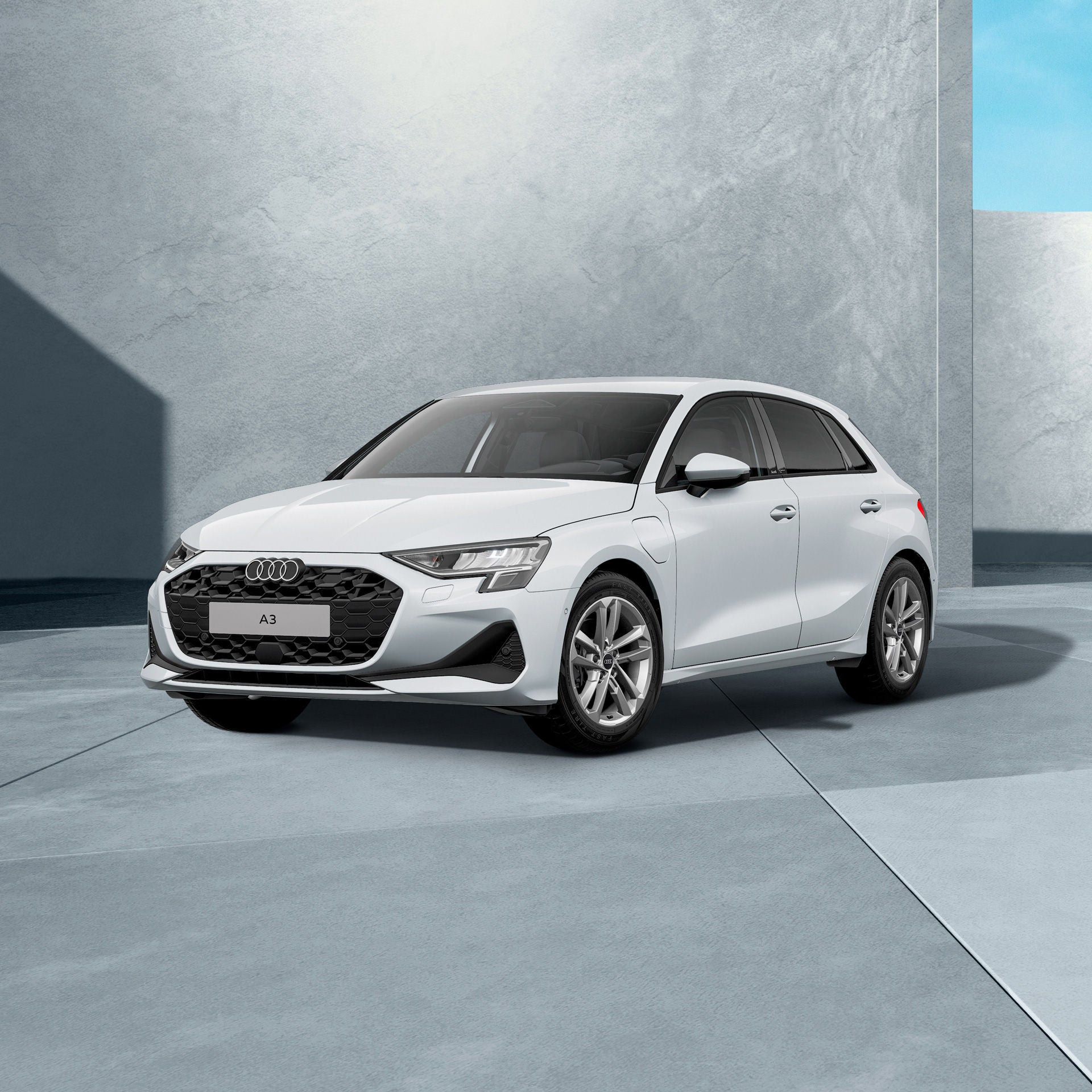 Ein gletschwerweiß metallischer Audi A3 Sportback von schräg vorne fotografiert vor einer modernen Kulisse.