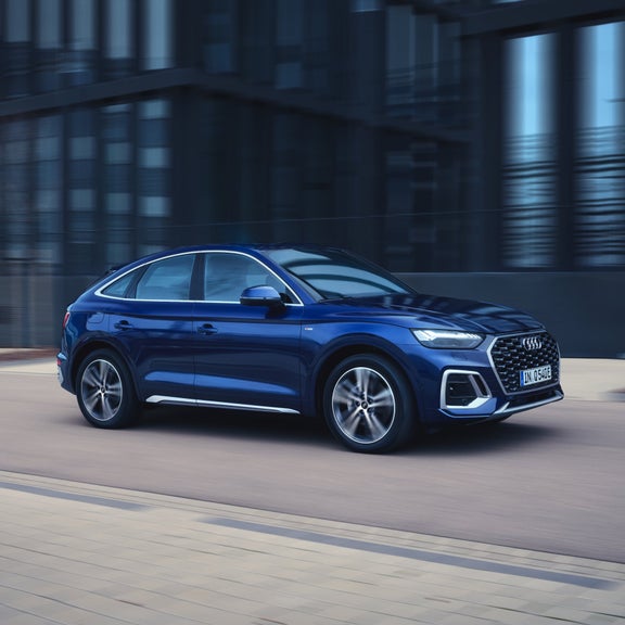 A blue sedan driving through an urban street, showcasing motion blur.