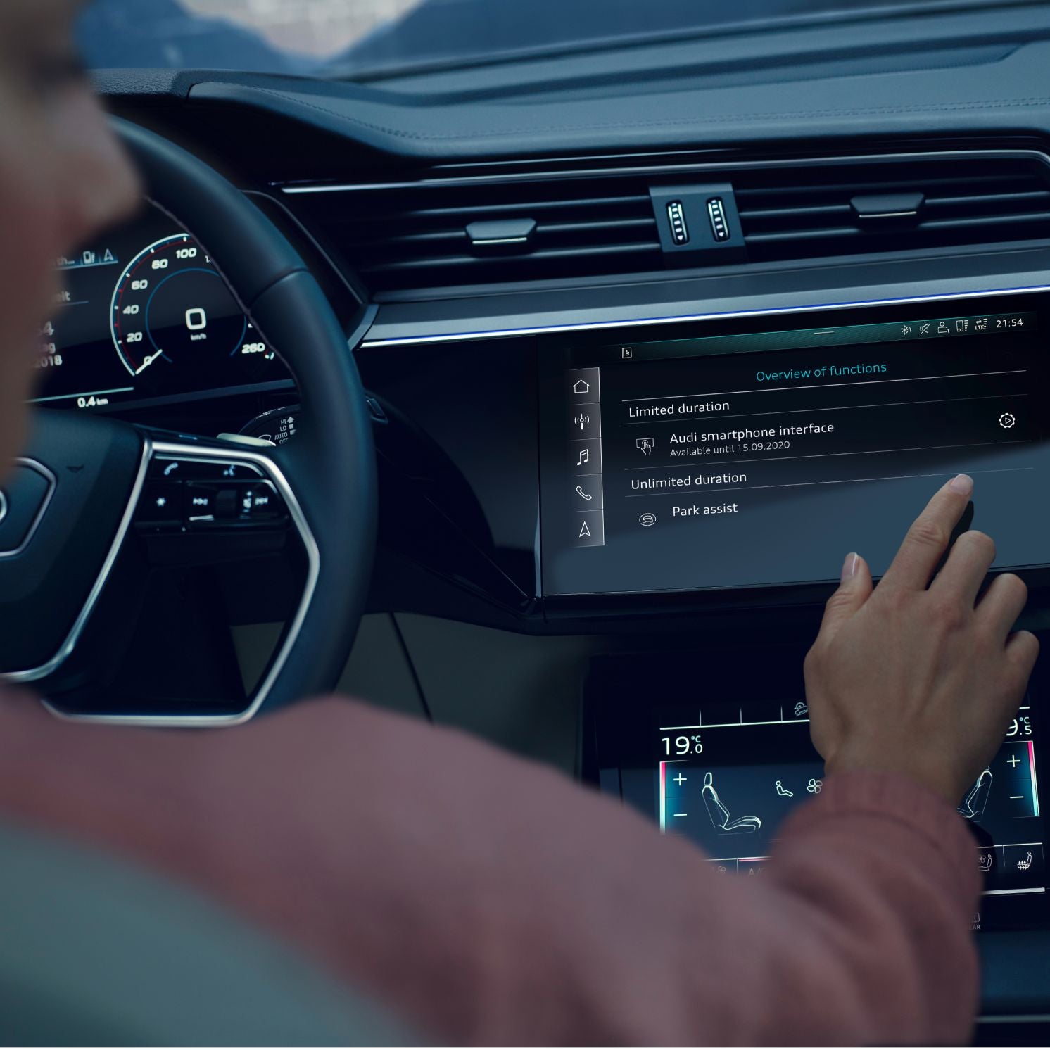A person in the driver seat of an Audi vehicle and interacting with the digital dashboard