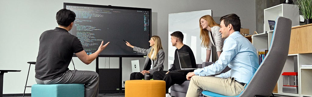Fünf Mitarbeitende von Audi sind im Gespräch und schauen sich etwas auf einem Bildschirm an