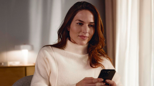 Kvinna som sitter med sin telefon i hemmamiljö