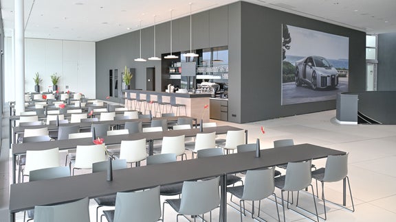 Frontansicht der „Audi drivers lounge“ mit Thekenbereich, Gläserregalen, Kaffeemaschine und mehreren Barhockern.