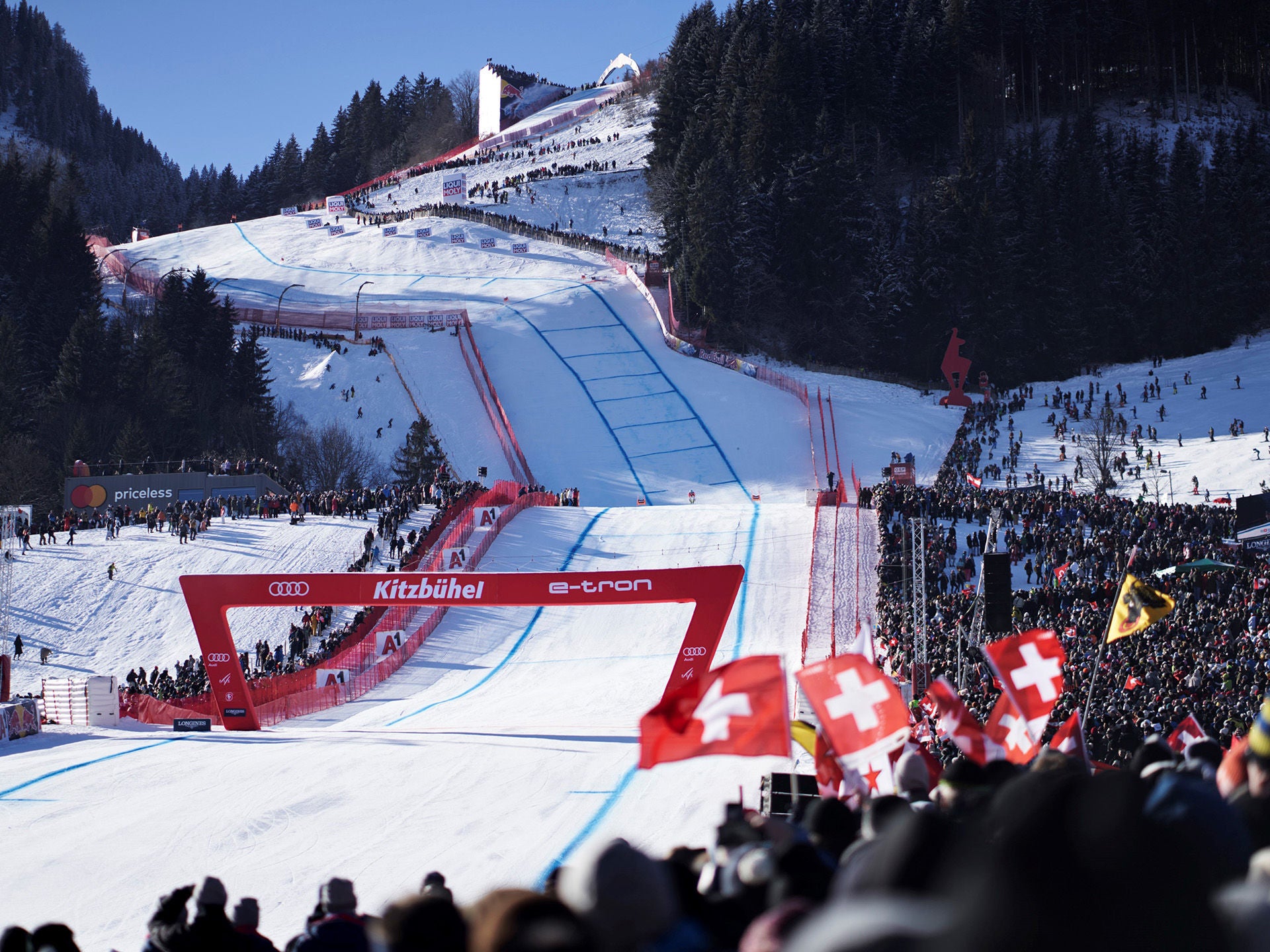 Ein Skifahrer kurz vor dem Zieleinlauf in Kitzbühel. Auf dem roten Zielbogen sind ein Audi-Logo und die Schriftzüge Kitzbühel und e-tron zu sehen.
