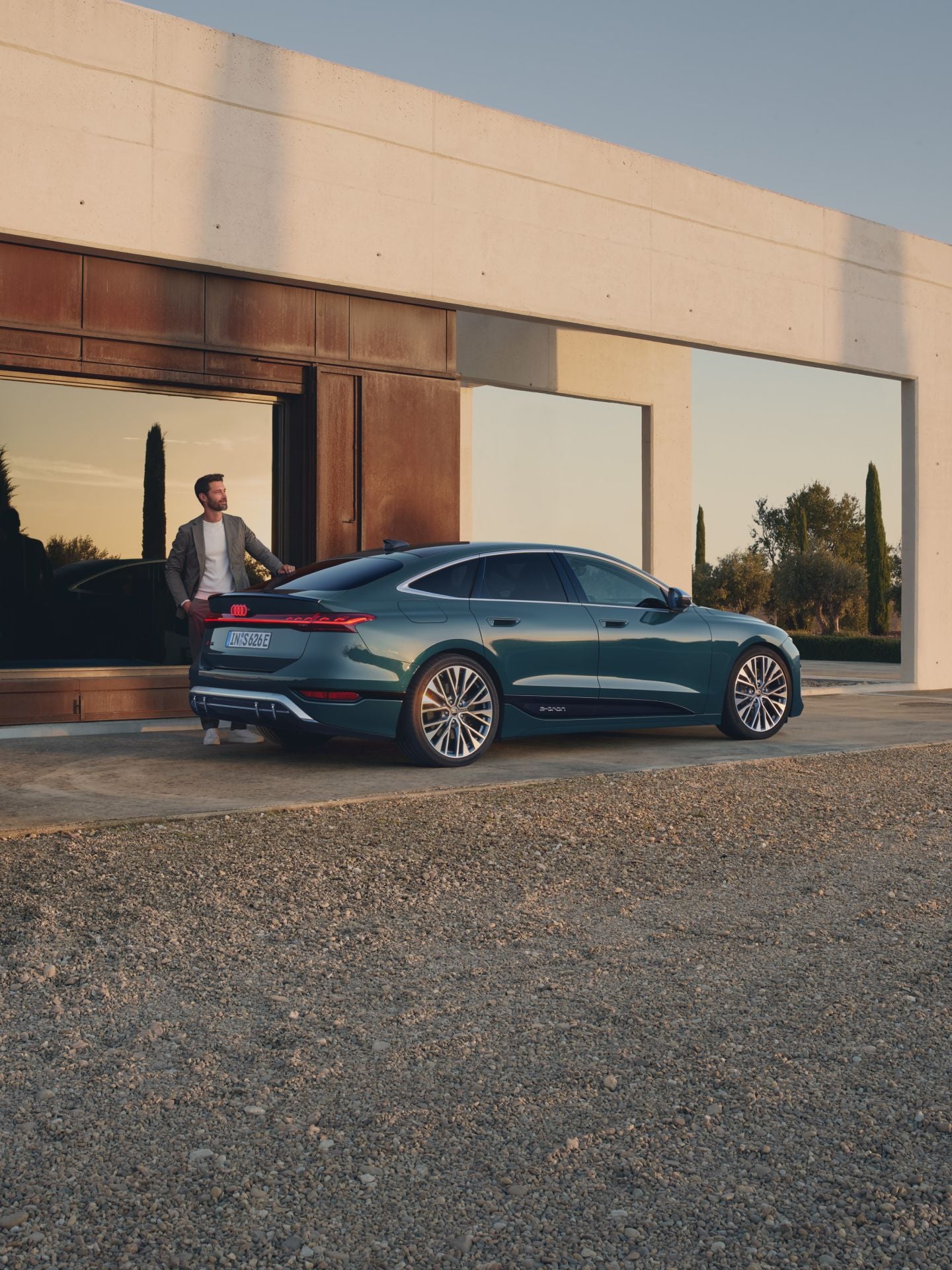 Sedan parked outside a modern house at dusk.