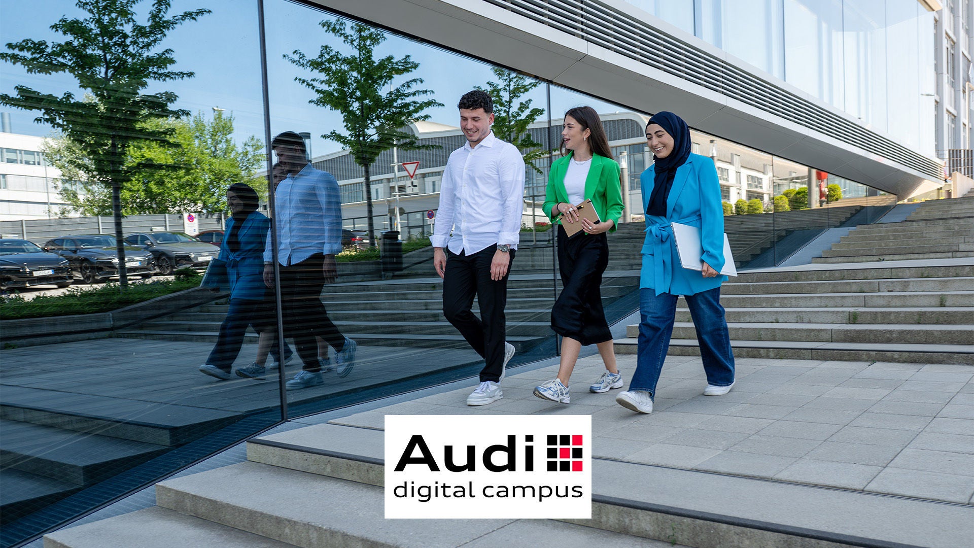 Drei junge Menschen sind im Gespräch und laufen an einem Gebäude entlang