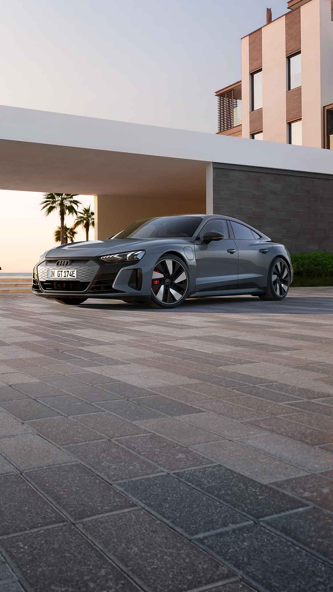 A grey sportscar parked outside near palm trees at sunset.