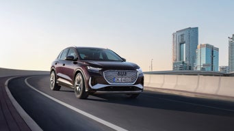 Audi Q4 e-tron travelling down a bridge road with city skyline in the background.