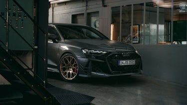 Das Sondermodell RS 3 competition limited schräg von vorne, in einer Werkstatthalle stehend, der hintere Teil des Fahrzeugs wird verdeckt von einer metallenen Treppe.