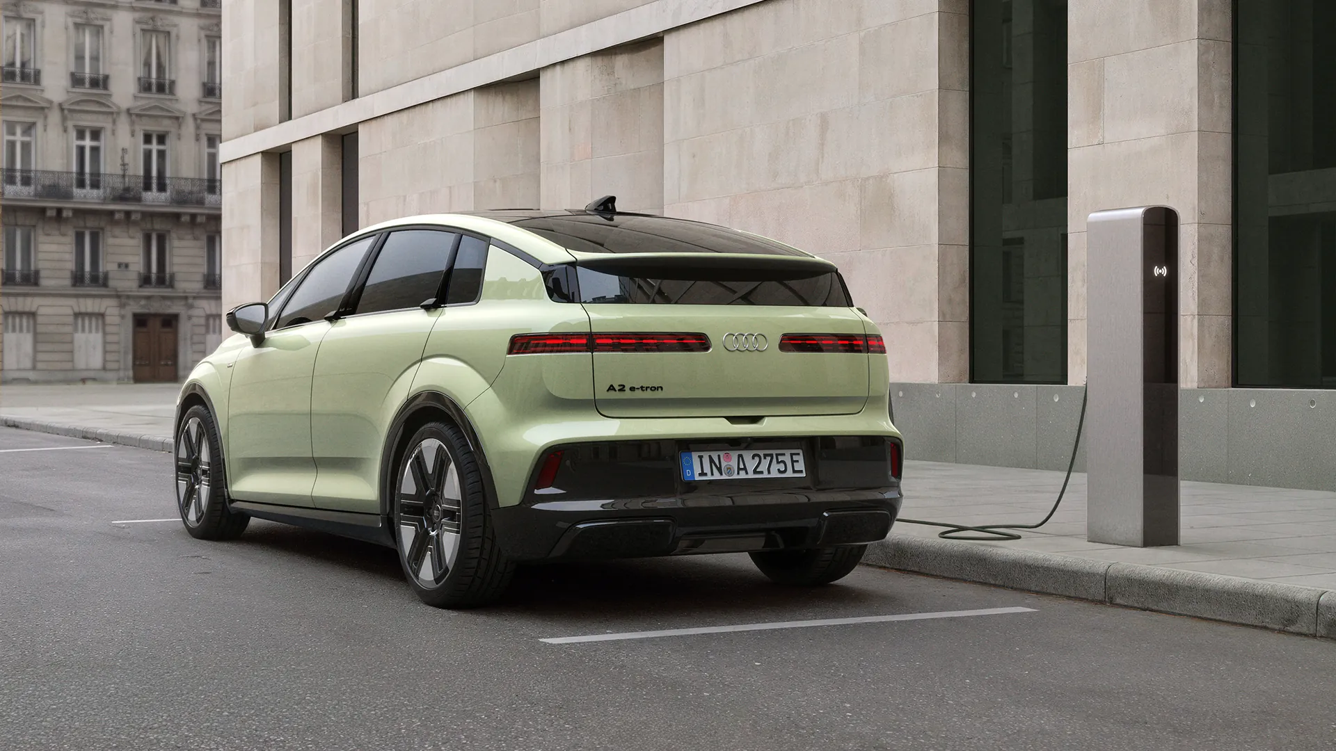 Pistachio green Audi A2 e-tron electric hatchback plugged into a charging station on a city street