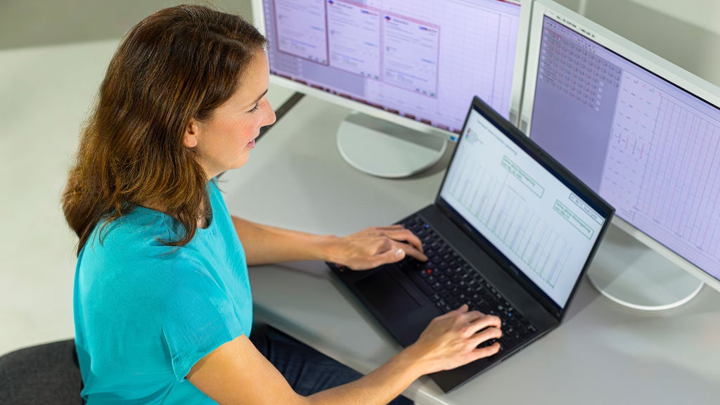 Meike is sitting at her laptop and has two extra screens in front of her
