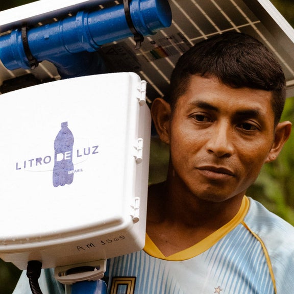 Ein mann trägt ein Solarmodul von Litro de Luz auf den Schultern.