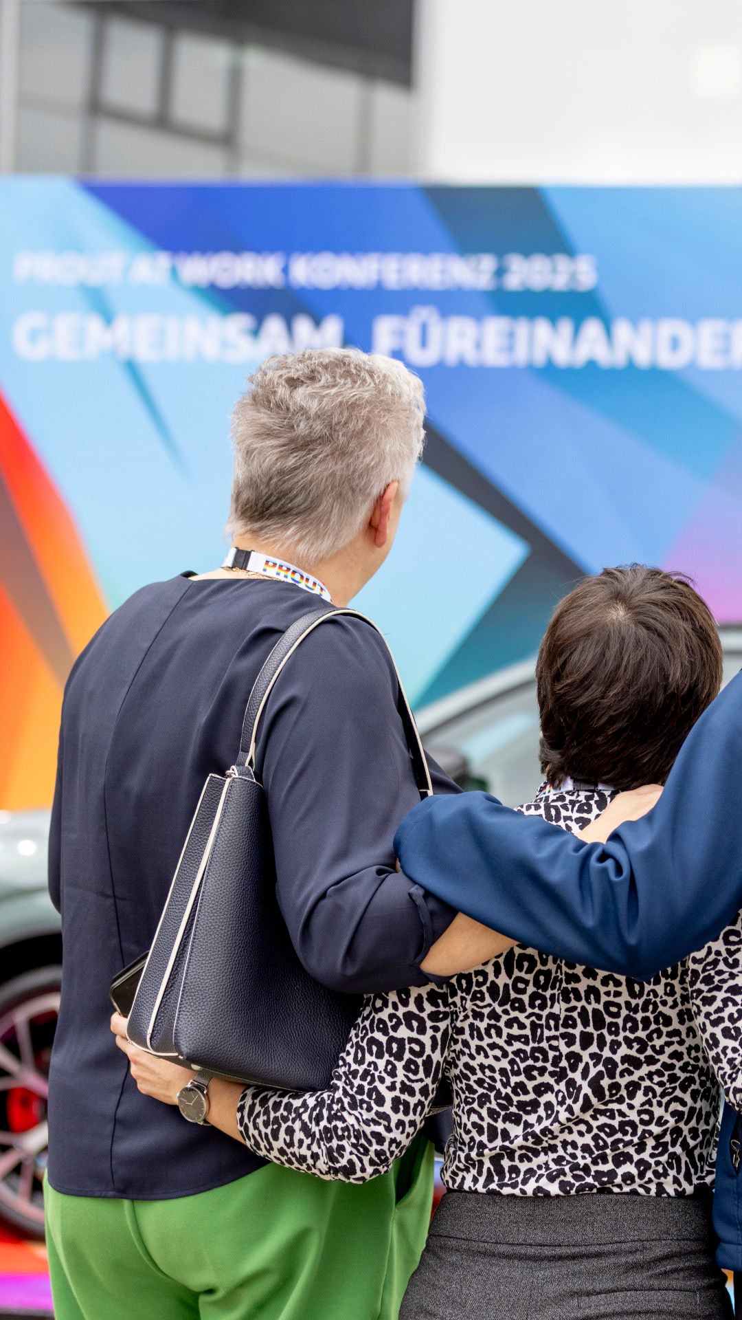 Mitarbeitende blicken Arm in Arm auf ein Plakat zum Thema Audi Diversity.