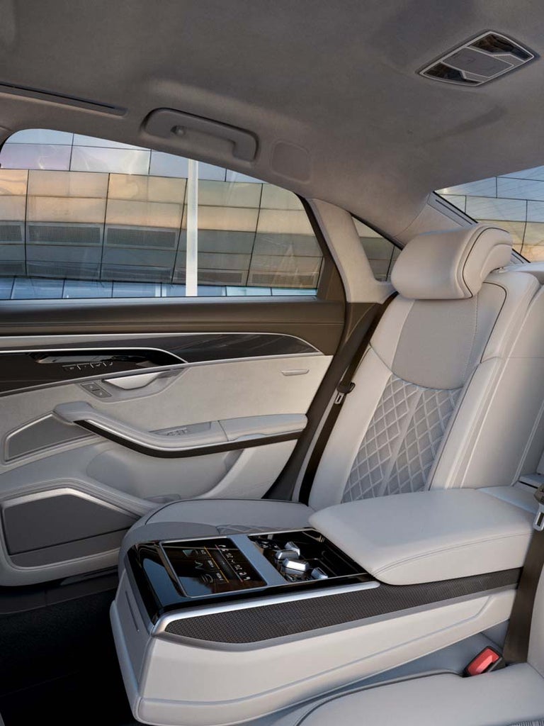 Rücksitze mit hellem Leder und Rautenmuster im Audi S8 TFSI, Mittelarmlehne mit Touchscreen, helle Türverkleidung sichtbar.