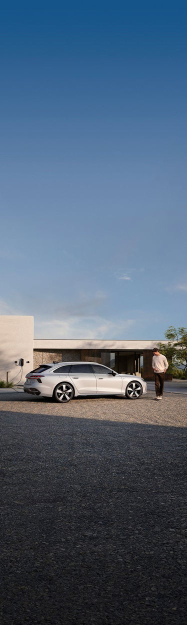 Audi A6 Avant e-hybrid bianca parcheggiata e collegata a una wallbox di ricarica