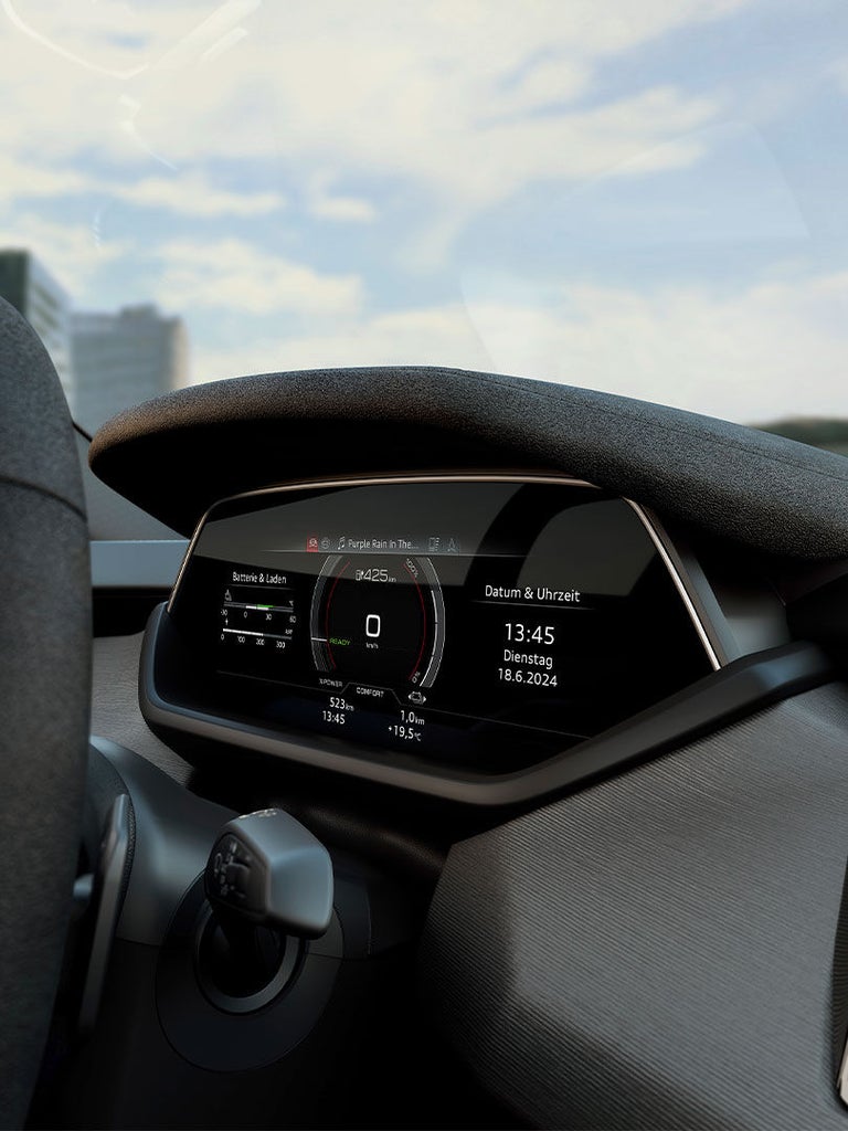 Nahaufnahme des digitalen Cockpits eines Audi S e-tron GT mit Tachometer, Batteriestatusanzeige und Datum/Uhrzeit. Das Display zeigt eine verbleibende Reichweite von 425 km und spielt das Lied „Purple Rain“.