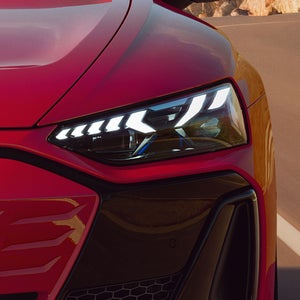 Nahaufnahme des Matrix LED-Scheinwerfer eines roten Audi e-tron GT quattro.