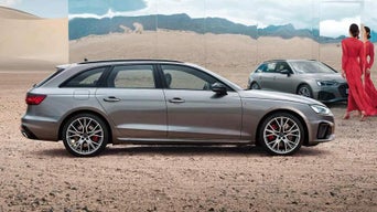 Grey Audi vehicle on desert terrain with a mirror reflecting another car and two people conversing