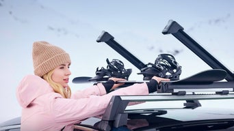 Vista posteriore di un SUV Audi con un box portaoggetti sul tettuccio, parcheggiata in un vialetto privato.