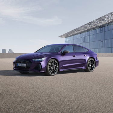 A purple Audi parked in front of a modern building with a clear sky background.