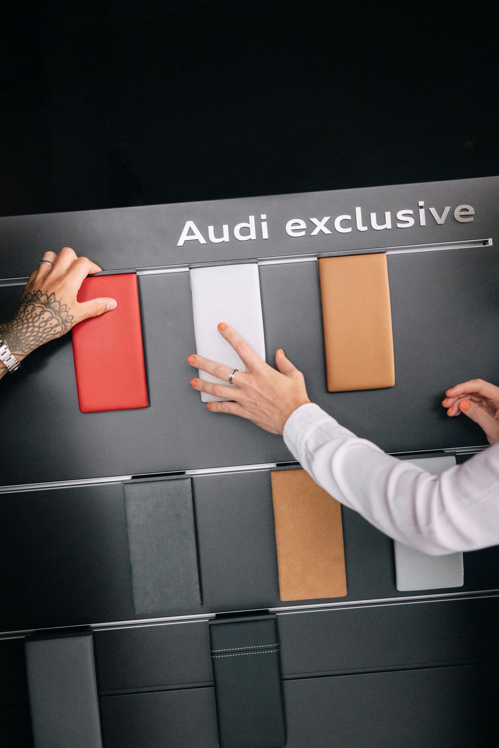 Beide greifen nach Mustern auf einer Ausstellungsfläche.