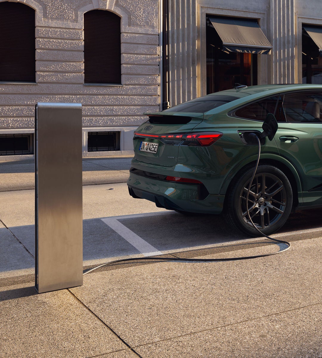 Vy över bakre del av Q4 Sportback e-tron parkerad vid en laddstation.