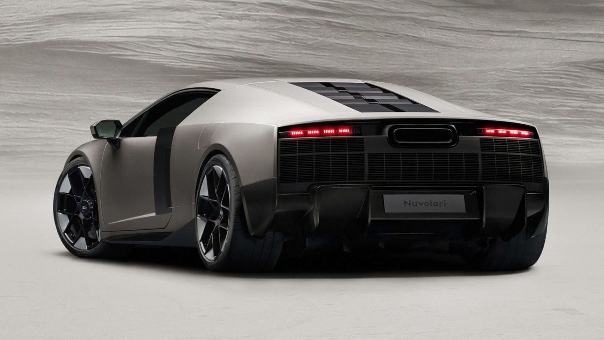 Dreiviertelansicht von hinten des Audi Nuvolari, die die plastisch geformten Heckflächen, den hoch angeordneten Auspuff und die markanten LED-Rückleuchten zeigt.