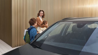 Eine Frau steht mit ihren beiden Kindern hinter einem Audi