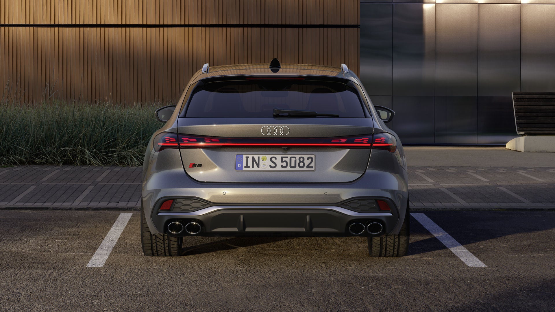 Heckprofil des S5 Avant, welcher auf einem Parkplatz vor einer Gebäudefassade steht.