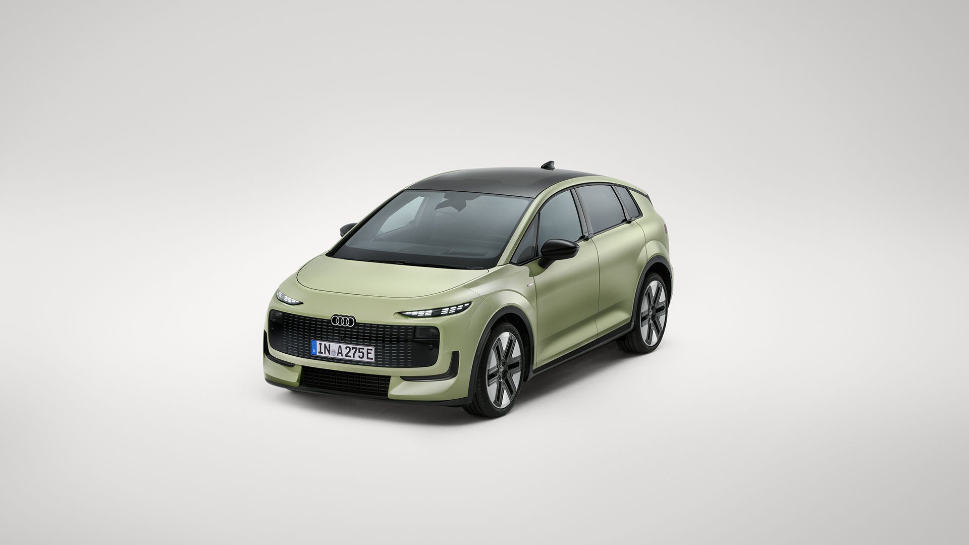 Une Audi A2 e-tron verte devant un fond de studio gris.