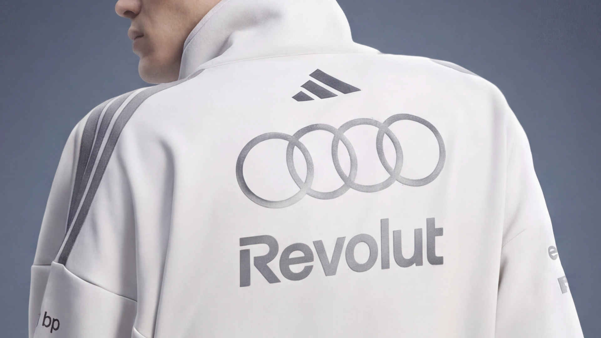  Back view of a white Adidas Audi Formula 1 team jacket featuring the four-ring Audi logo and Revolut sponsorship
