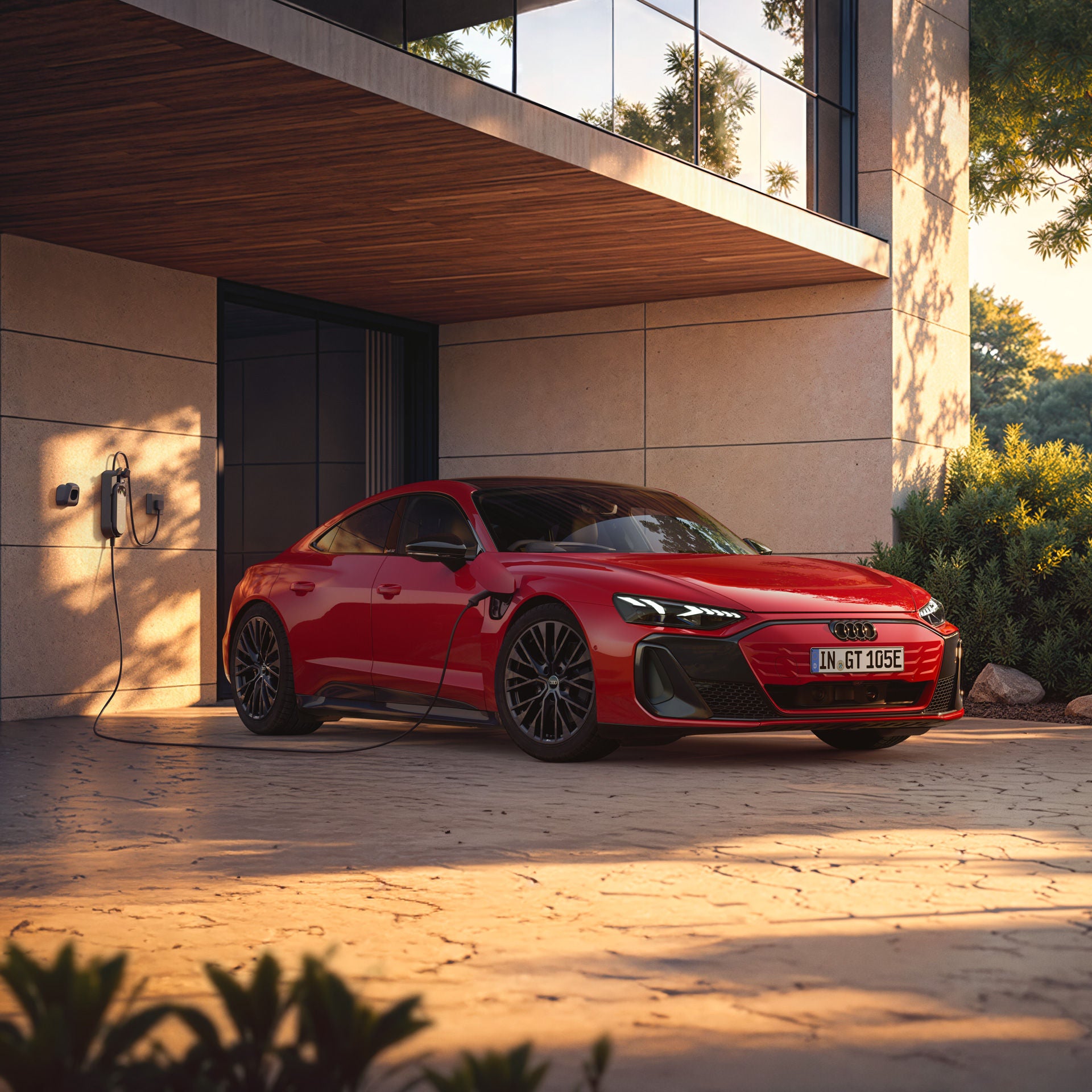 Red Audi e-tron GT quattro parked in front of a modern building, connected to a wallbox.