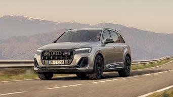 An Audi SUV driving on a road with mountains in the background.