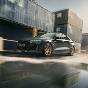 Das Sondermodell RS 3 competition limited schräg von vorn in voller Fahrt vor einer Container-Kulisse.