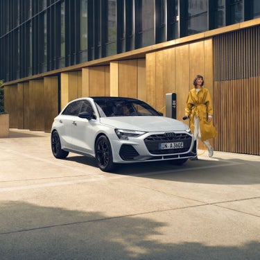 person wearing a yellow coat standing next to white Audi A3 