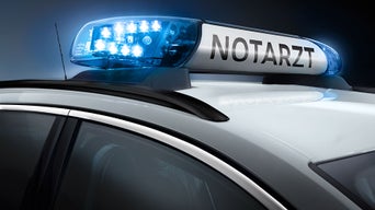 Blaulicht mit der Aufschrift „Notarzt“ auf dem Dach eines Einsatzfahrzeugs bei Nacht.