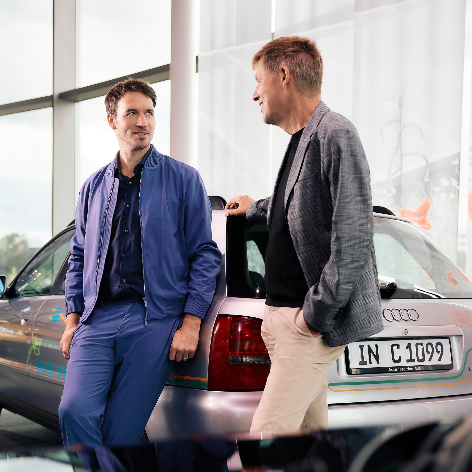 Rüdiger Recknagel und Felix Neureuther stehen vor einem silbernen Audi Modell und unterhalten sich.