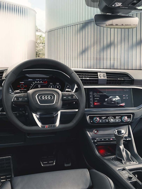 Foto del interior del Audi RS Q3 donde se ve el volante deportivo de cuero y la consola central. 