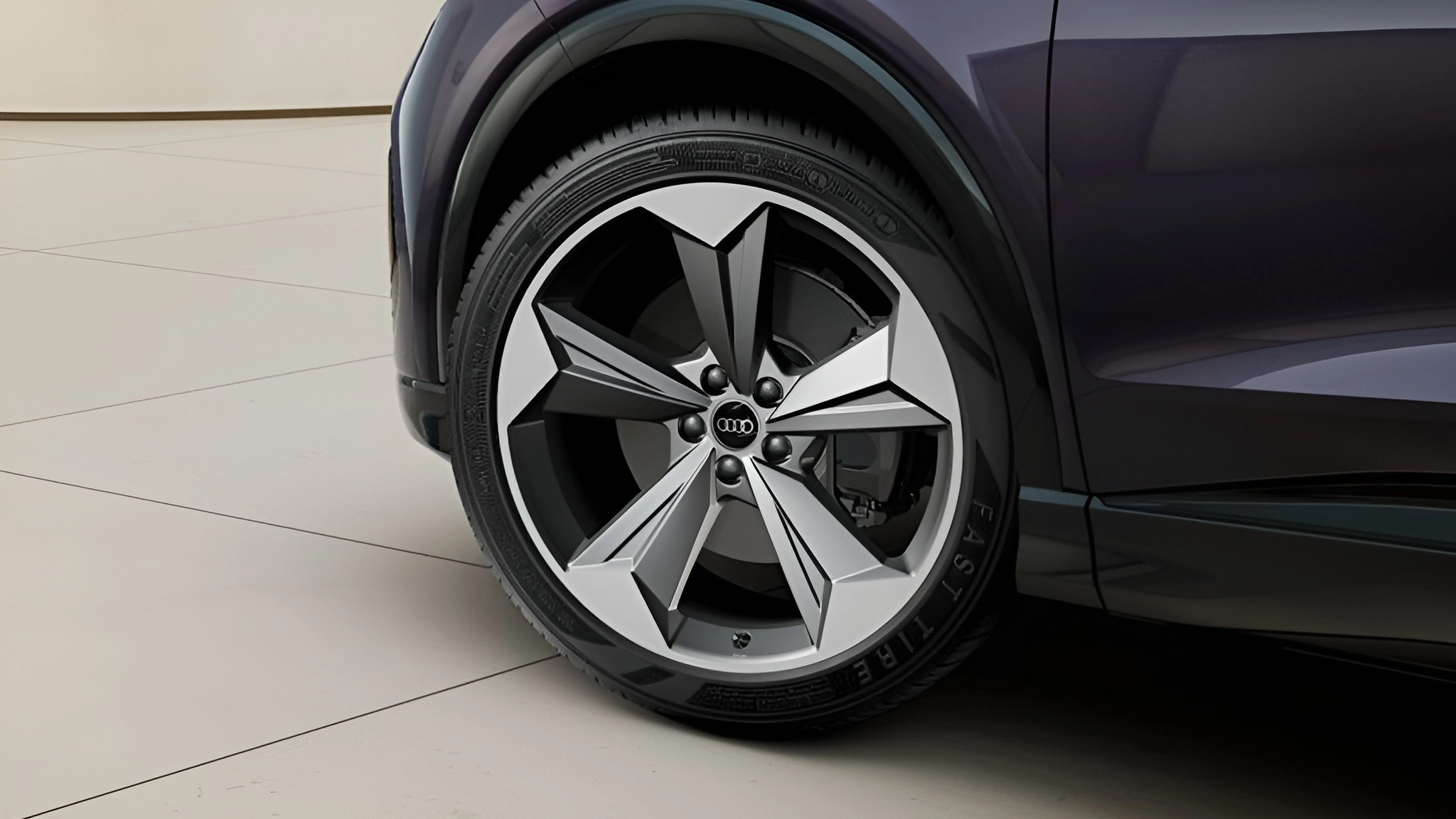 Dark purple Audi Q4 e-tron car wheel and tyre on off-white tiled floor.