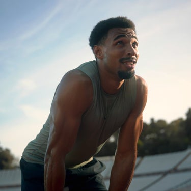 Leo Neugebauer in der Pause nach einer anstrengenden Übung. Die Hände sind auf die Knie gestützt, in seinem Blick ist Erschöpfung aber auch Zufriedenheit zu erkennen.