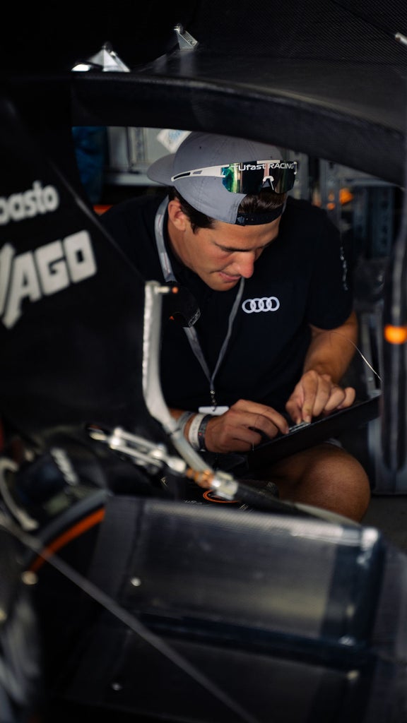 Eine Person steht an der Tür eines Fahrzeugs und hält ein Gerät in der Hand auf das er schaut