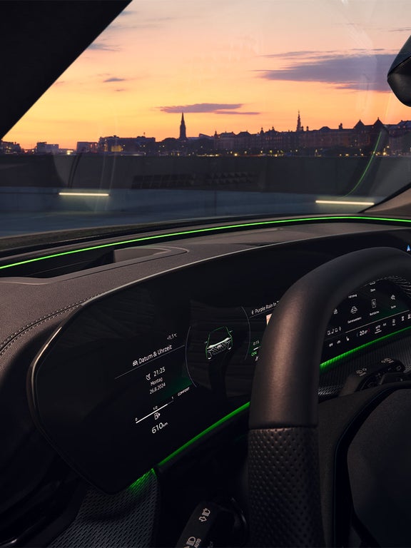Digitales Cockpit im Audi SQ5 SUV bei Nacht mit grünem Lichtband und Stadtpanorama im Hintergrund.