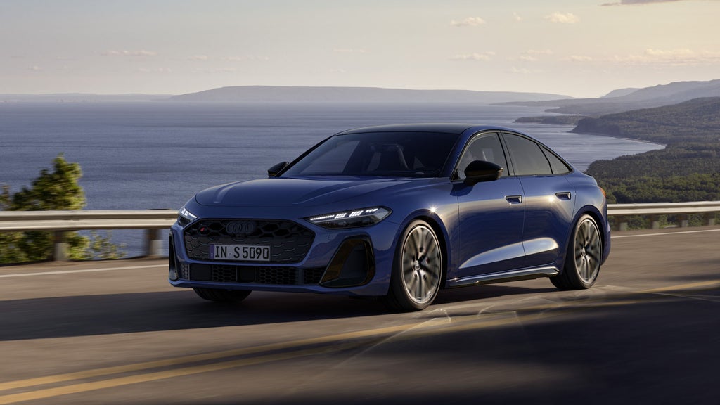 Die S5 Limousine in dunkelblau fährt auf einer Straße entlang der Küste.