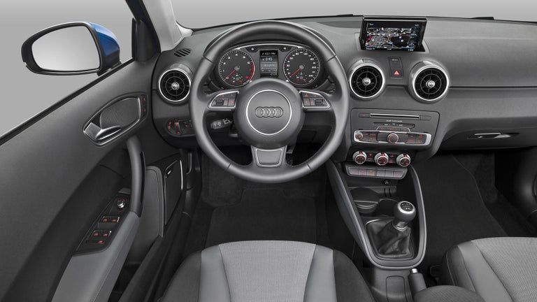 Blick ins Cockpit eines Audi mit schwarzem Lenkrad, Rundinstrumenten und Navigationsdisplay.