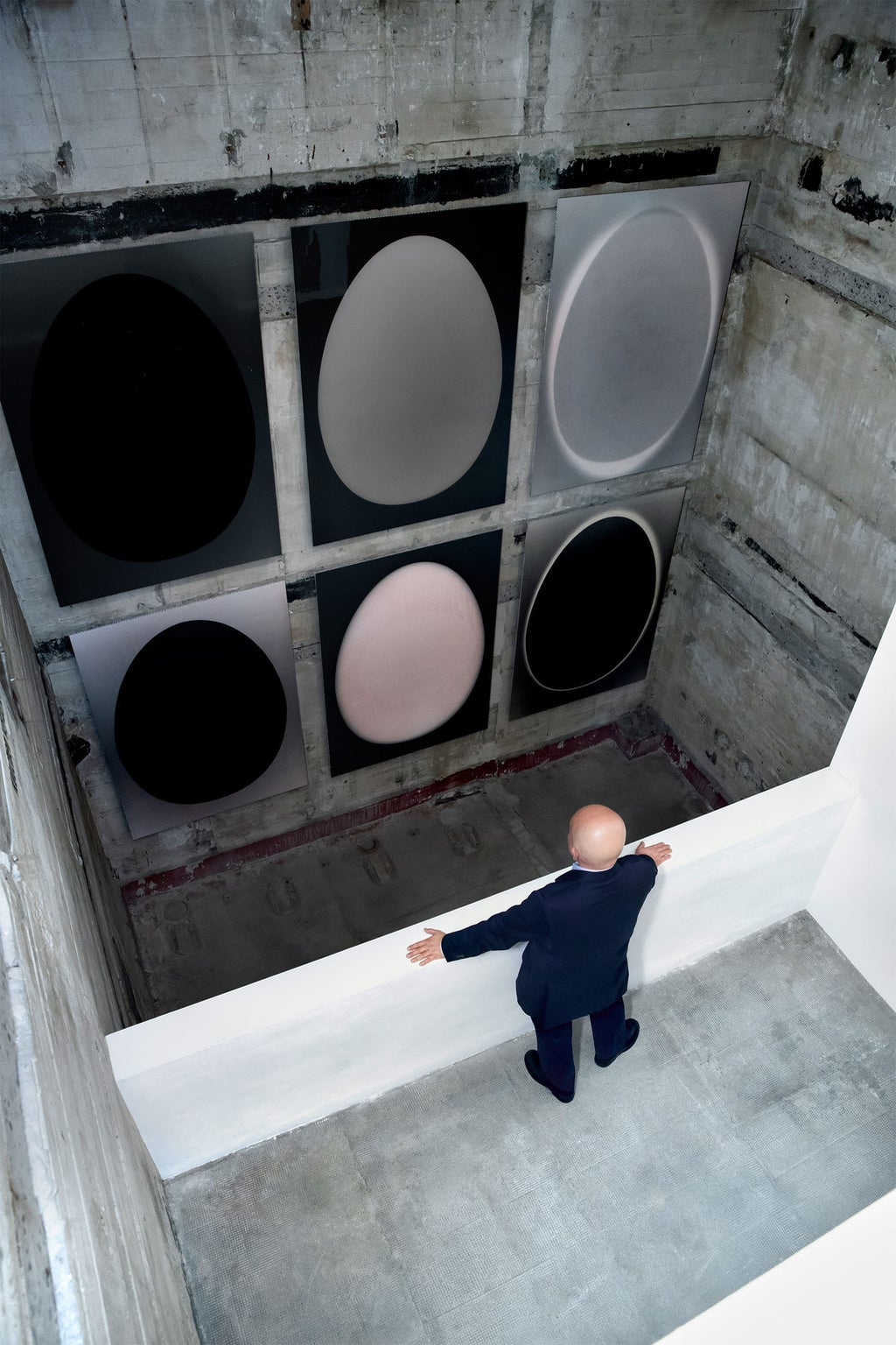 Christian Boros regarde des œuvres d'art sur un mur.