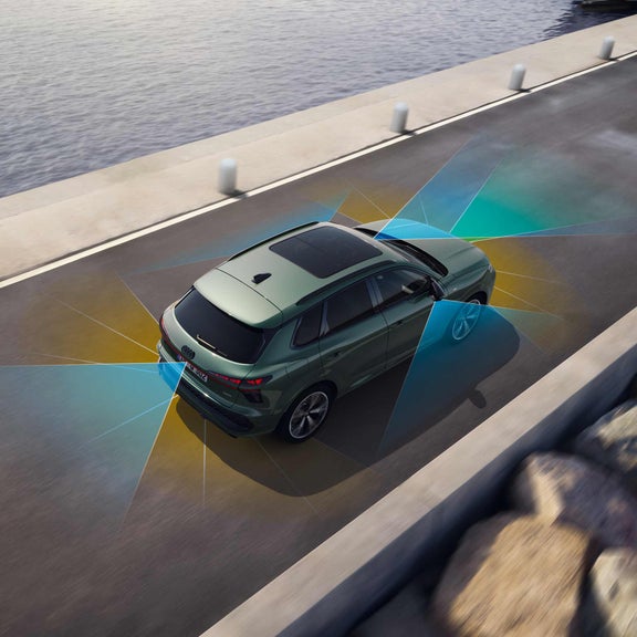 The Q3 SUV on a public road. The image shows the adaptive driving assistant's detection of lane boundaries marked in blue and yellow.