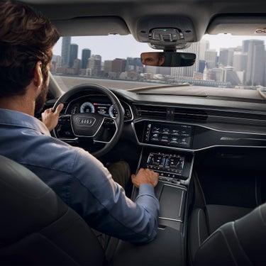 Person driving a car with a sleek dashboard and touch controls.