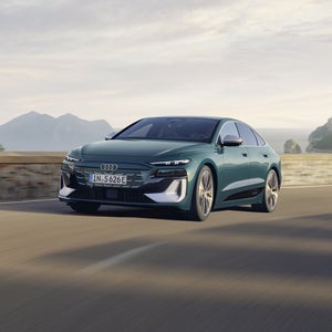 Der S6 Sportback e-tron im schrägen Frontprofil, während er eine Küstenstraße entlangfährt.