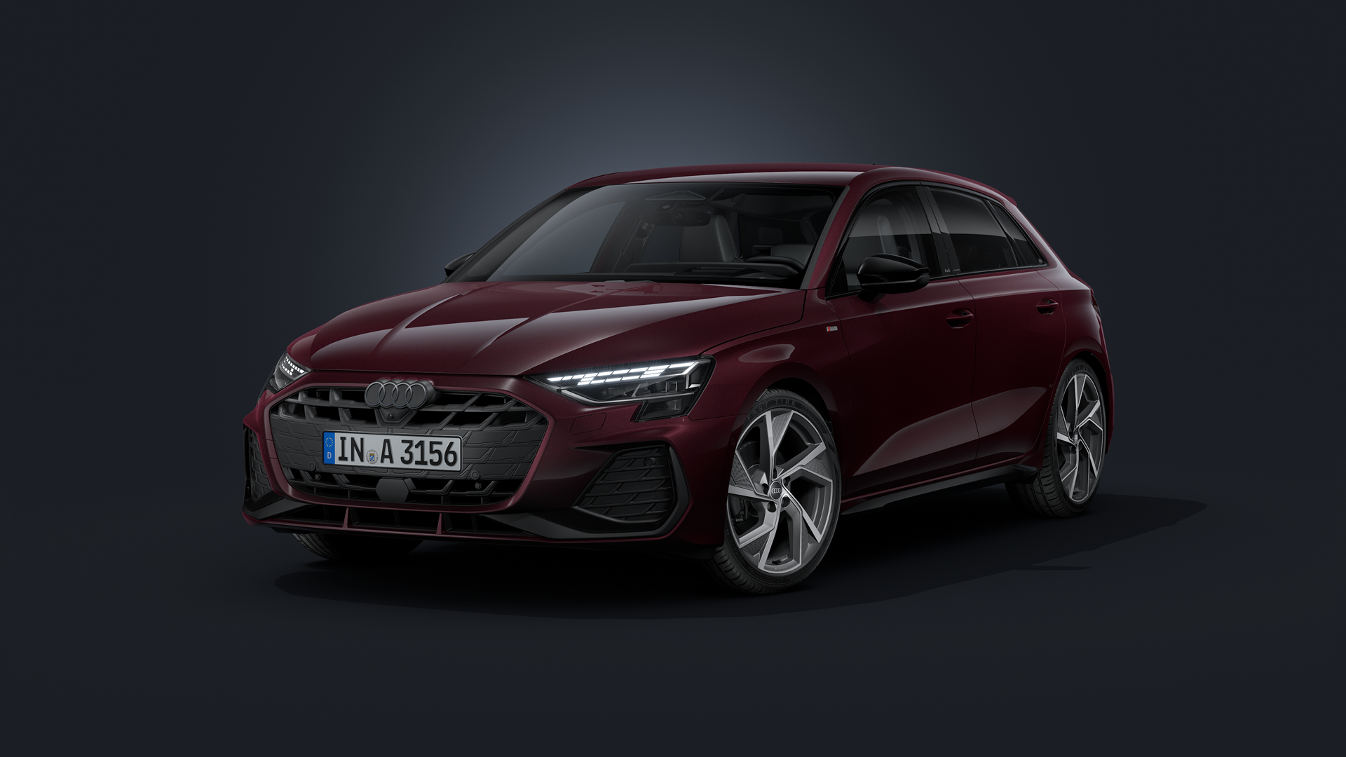 Der Audi A3 Sportback mit Individuallackierung Audi exclusive in Shirazrot Metallic schräg von vorne auf dunklem Hintergrund.